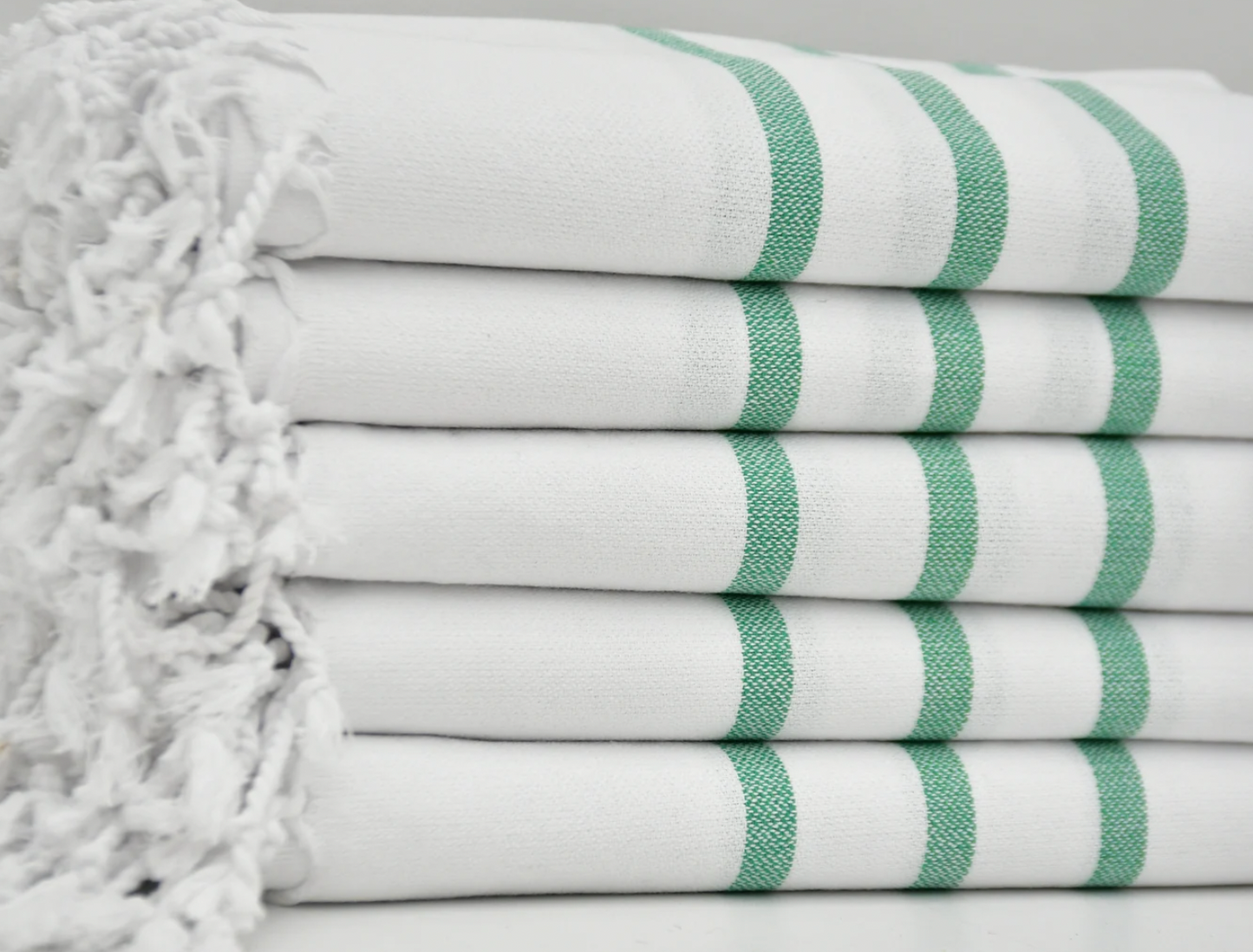Picture shows white tasselled hand towel with three green stripes.